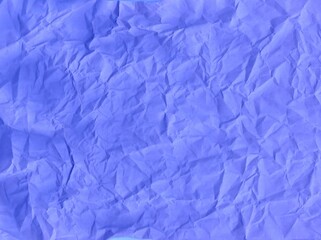 Obraz premium Crumpled blue wrapping paper with a solid background.