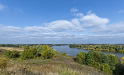 Autumn landscape with a view of the river and endless expanses of fields. Panoramic landscape with river and field and trees.