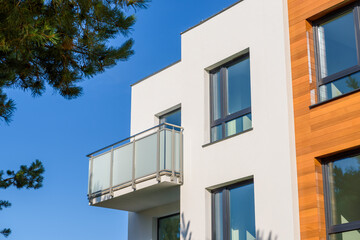 Modern apartment building with balcony against a blue sky.