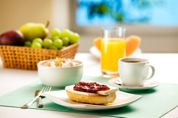 Mesa de café da manhã brasileiro com pães, frutas, suco e cereal matinal