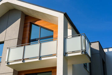 Modern apartment building with balcony against a blue sky.