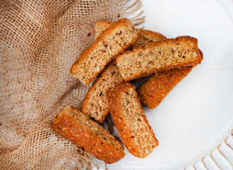 Traditional South African  bran fiber rusks with rustic burlap cloth on white plate with copy space
