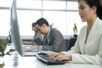 Asian man worker stress working in office. Employee sitting serious and tired from work. Work and life balance.