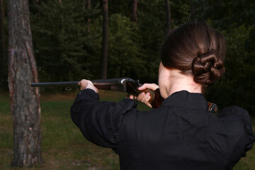 Woman with vintage shotgun in the forest