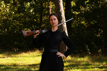 Woman with vintage shotgun in the forest