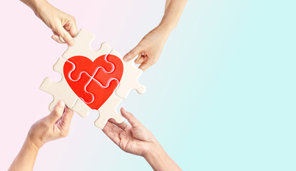 Hands holding white jigsaw with red heart shape inside on light pastel background, Together with Love, complete of love relationship, and Love can make different concept