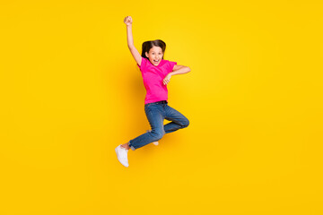 Photo of excited small girl jump enjoy horse rodeo wear pink t-shirt jeans shoes isolated yellow...