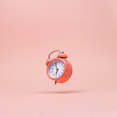 The pink alarm clock is levitate in the air, against a pink background. The concept of time, copy...