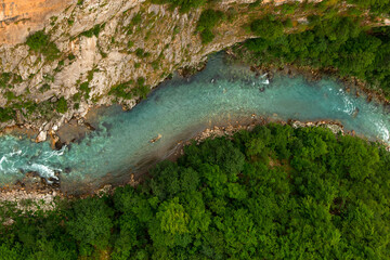 Mountain beautiful river with clear blue water, in the middle of the forest and stones. Natural untouched nature. Top view.