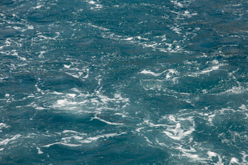 Fototapeta na wymiar Bubbling water and sea foam from the motor of the boat, concept of water movement, gravel sea color.