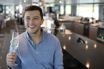 Handsome young man drinking champagne at bar 