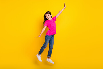 Fototapeta na wymiar Photo of funky sporty glad girl jump enjoy weekend wear pink t-shirt jeans sneakers isolated yellow color background