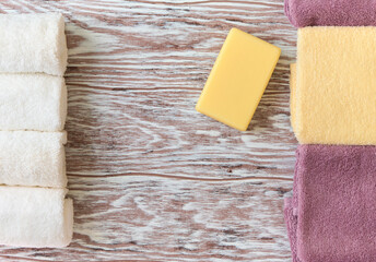 Yellow soap bar and folded rustic towels on a wooden surface with copy space