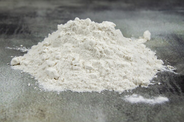 Fototapeta na wymiar pile of sifted flour, dark concrete tabletop background. handful of white flour on black background