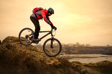 Fototapeta na wymiar Cyclist Riding the Mountain Bike on the Rocky Trail at Cold Autumn Evening. Extreme Sport and Enduro Cycling Concept.
