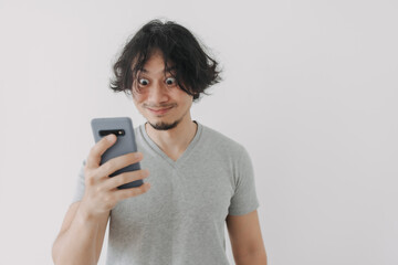 Funny and happy face of Asian man look at his smartphone on white background.