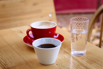 Aromatic coffee in a red cup with milk foam and coffee in a white cup. 