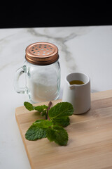 Seasoning Cockerel, containing salt shaker and olive oil on a wooden board on a marble table