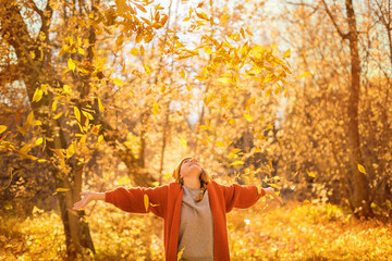a girl throws autumn leaves in an autumn park