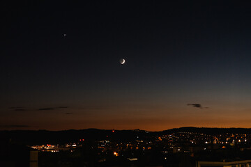 waxing crescent moon over city