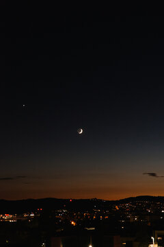 waxing crescent moon over city