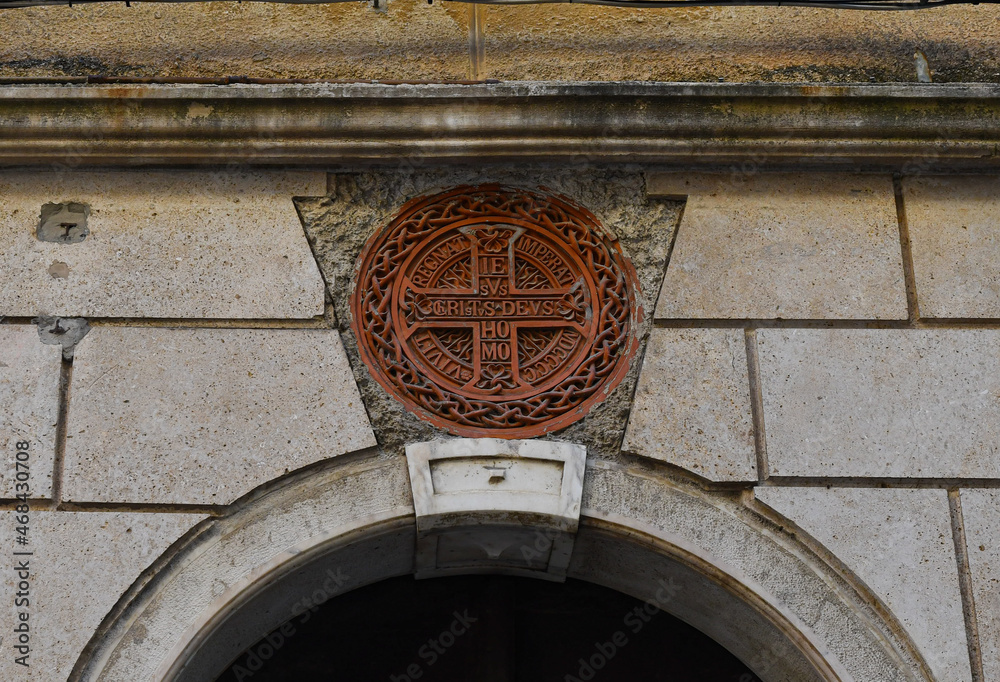 Poster Close-up of a terracotta plate with the symbols of Jesus Christ on the façade of an old building in the historic centre of Alassio, Savona, Liguria, Italy