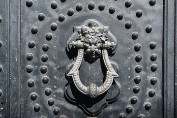 Close-up of an antique iron door with studs and a knocker ornated with a demon face, Alassio,...