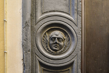 Detail of the slate frame of the portal of the Church of Charity with a bas-relief representing an angel or putto, Alassio, Savona, Liguria, Italy