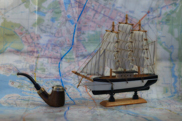 Model of a sailboat and a smoking pipe on the background of the map.