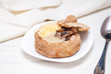 Creamy soup with mushrooms and cheese in bread.