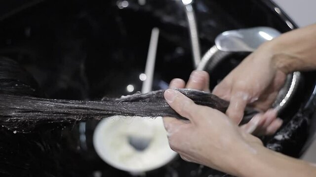 Sal&oacute;n de belleza, cuidado de pelo y concepto de personas. El profesional del sal&oacute;n de belleza lava el pelo con agua.