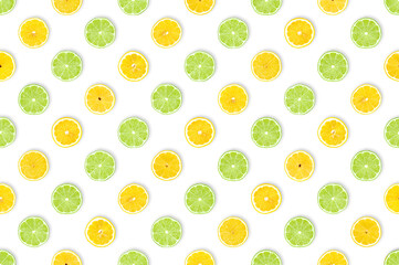 Lemon meets lime: healthy fruits background. Pattern of freshly cut lemon and lime slices against white background. Table top view, flat lay.
