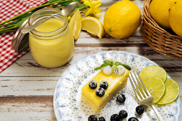 Slice of homemade lemon curd cake in the shape of an ingot or brick, a jar with the lemon curd...