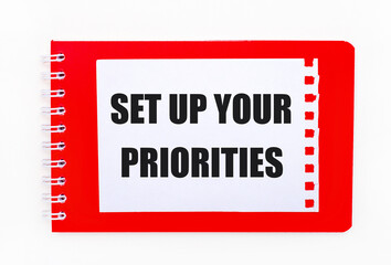 On a white background - a bright red notebook on a spiral. On it is a white sheet of paper with the...