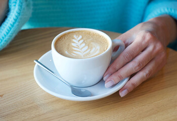 Cappuccino on the table. The girl is drinking coffee in a cafe.