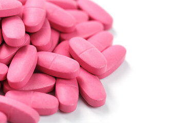 Obraz na płótnie Canvas Pink vitamin pills for women on a white background.