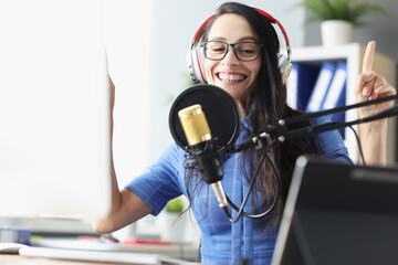 Smiling presenter woman in headphones speaking into microphone in studio