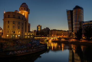 Obraz premium Vienna cityscape with modern Uniqa and Urania tower on the water channel at night, Austria
