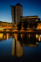 Vienna cityscape with modern Uniqa building reflected on the water channel at night, Austria