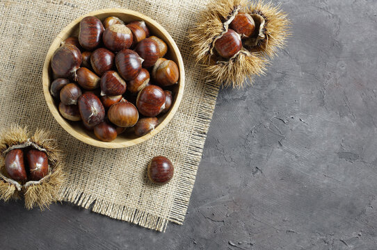 Fresh raw chestnuts on rustic table, Chestnut with thorny branch