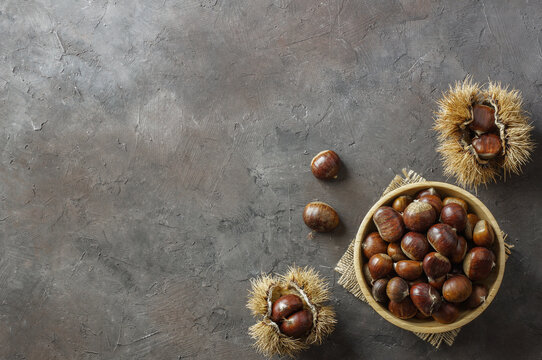 Fresh raw chestnuts on rustic table, Chestnut with thorny branch
