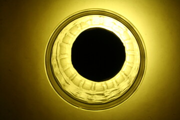 Vaso de vidrio con textura iluminado desde abajo con luz amarilla produce un diseño abstracto con...