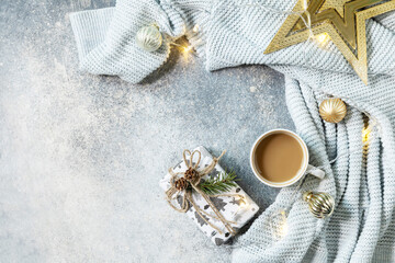New Year's or Christmas composition. Cup of coffee, christmas star, knitted blanket, garland and gift on a gray background. Winter concept. Flat lay, top view, copy space.