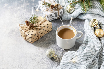 Obraz na płótnie Canvas Christmas composition with cup of coffee, knitted blanket, garland and gift on a gray background. Winter, Christmas concept. Copy space.