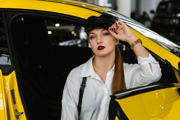A young girl in a cap sits in a yellow car, taxi