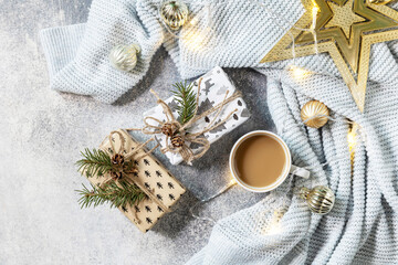 New Year's or Christmas composition. Cup of coffee, christmas star, knitted blanket, garland and gift on a gray background. Winter concept. Flat lay, top view.