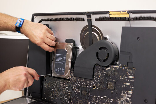 Technician replacing a hard drive and a computer screen during desktop repair