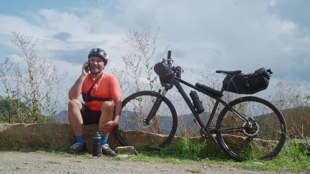 Cycle touring man talking on the phone in nature while traveling