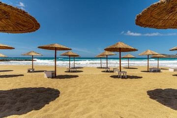 Fototapeta na wymiar Empty sandy beach with umbrellas in summer with sun light.