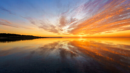 Fototapeta na wymiar Orange sunset on a quiet lake, sunset reflected in calm water